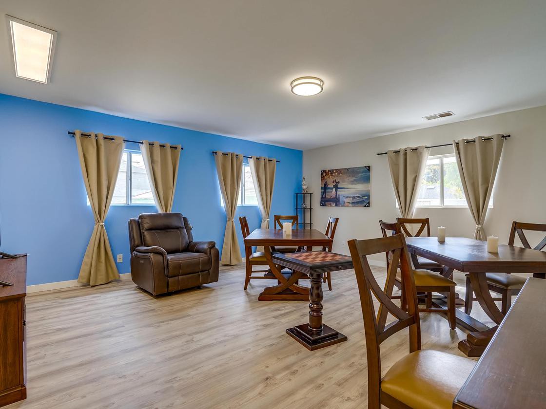 A spacious living and dining area with a blue accent wall, comfortable seating, and warm wooden flooring.