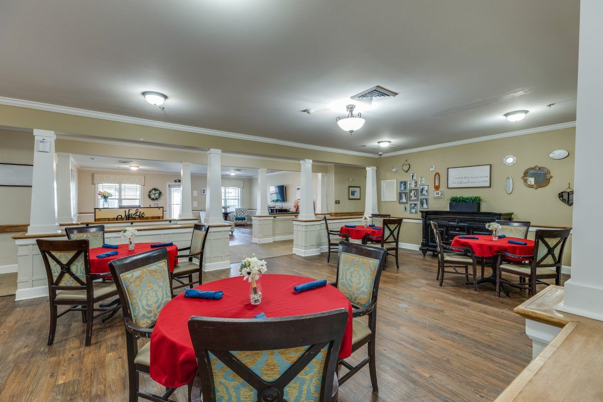 A spacious dining room with tables covered in red tablecloths and neatly arranged chairs.