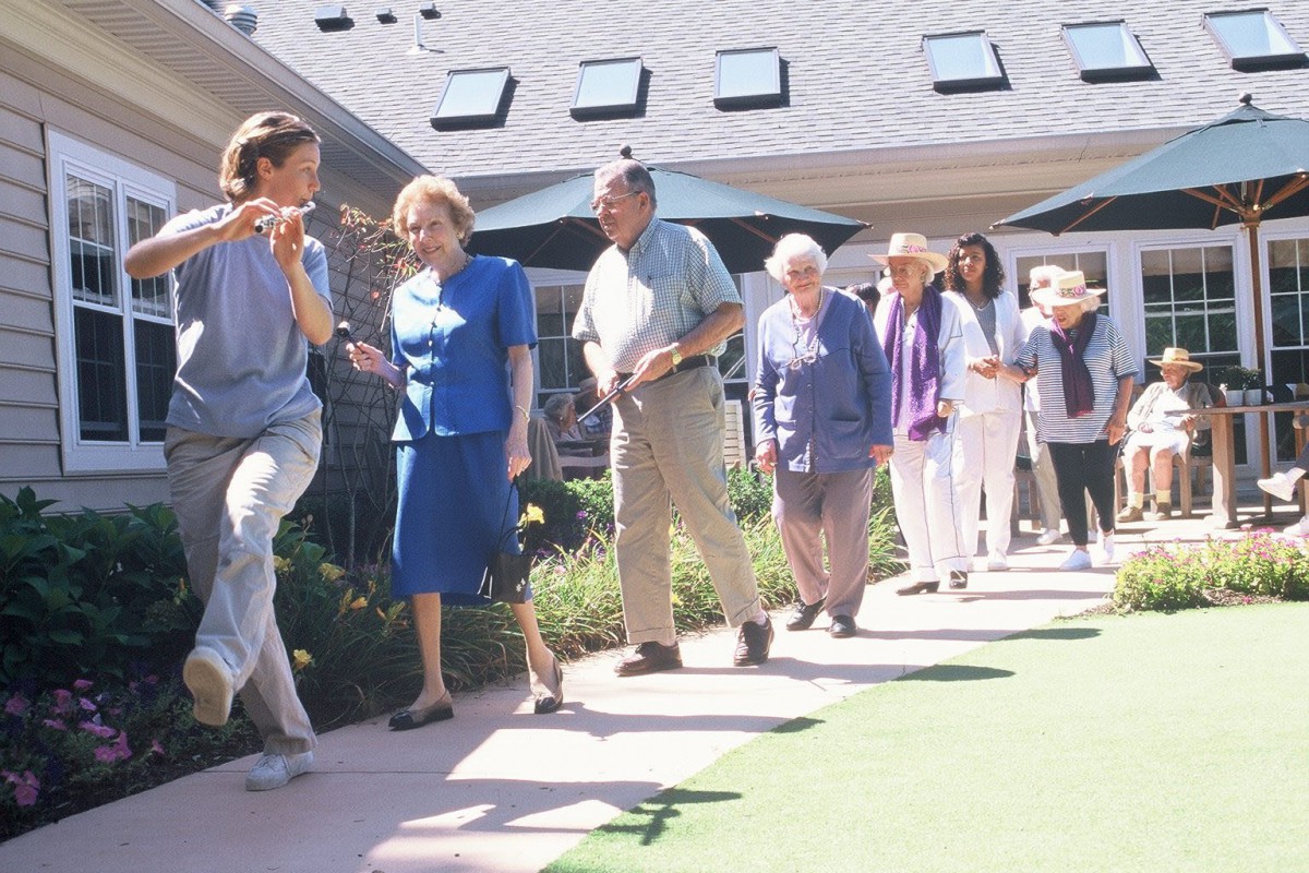 A group of seniors enjoying a walk together in a sunny outdoor setting.