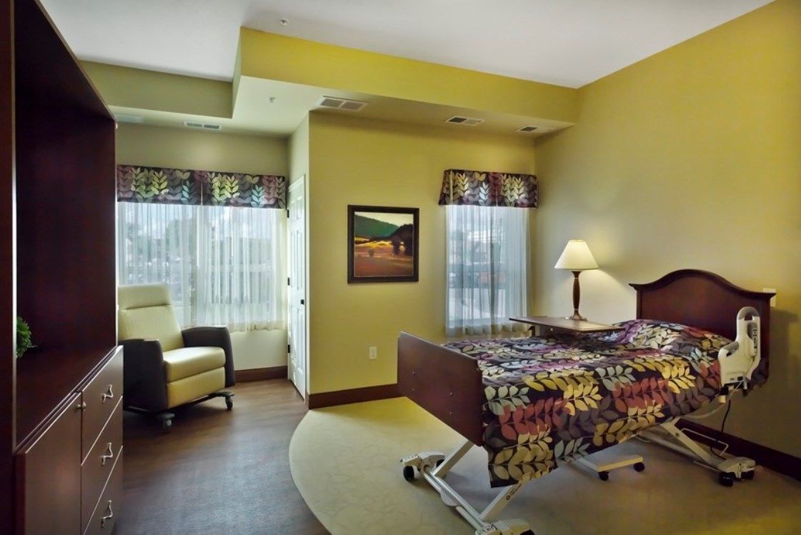 A well-lit hospital room with a bed and comfortable seating.