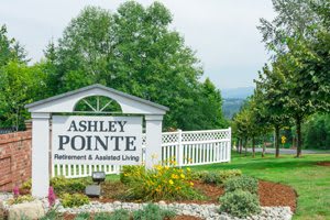 Entrance sign for Ashley Pointe Retirement & Assisted Living surrounded by greenery.