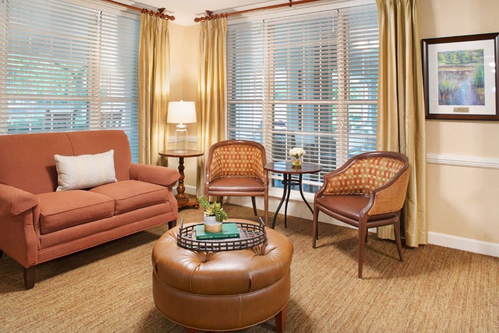 A cozy living room with a sofa, wicker chairs, an ottoman, and soft lighting.