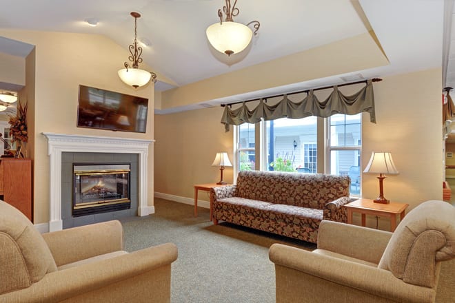 A cozy living room featuring a fireplace, comfortable seating, and large windows.