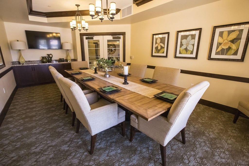 A spacious dining room with a long wooden table, elegant chairs, and chic decor.