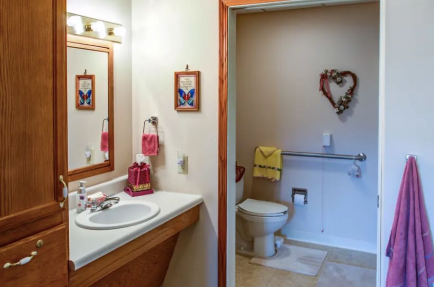 A cozy bathroom with a sink and mirror, featuring decorative wall art and neatly arranged towels.