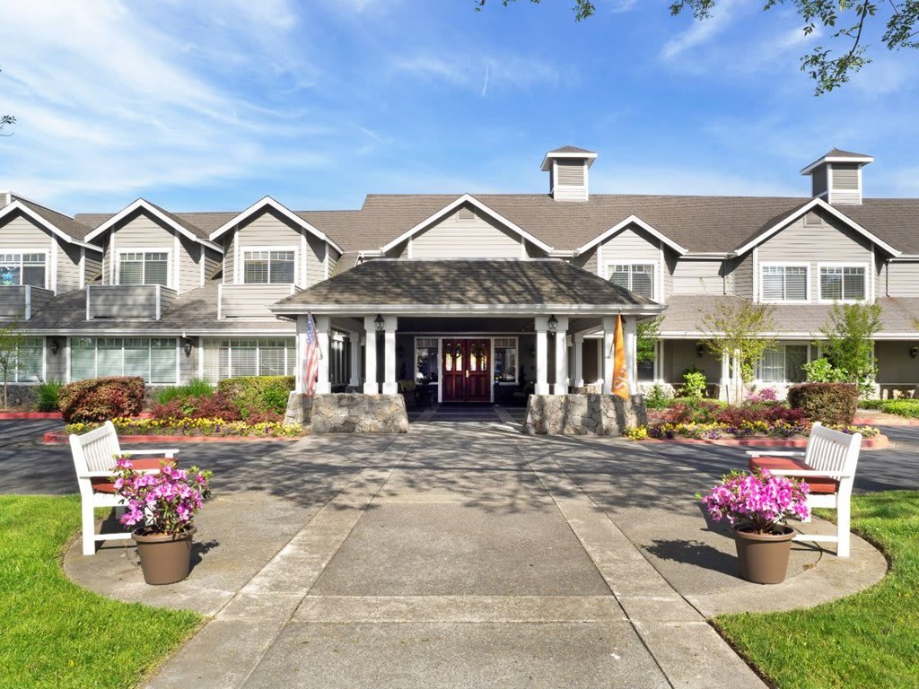 A beautifully landscaped building entrance with flowers and a clear blue sky.