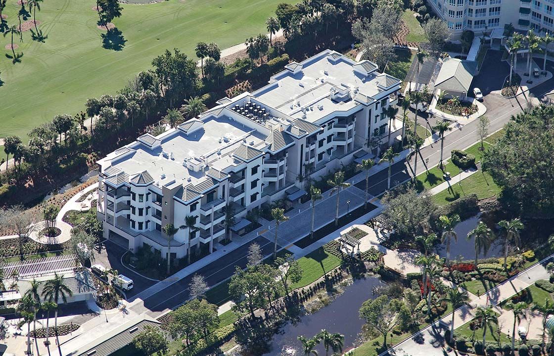 Aerial view of a luxury apartment building surrounded by trees in an urban area.