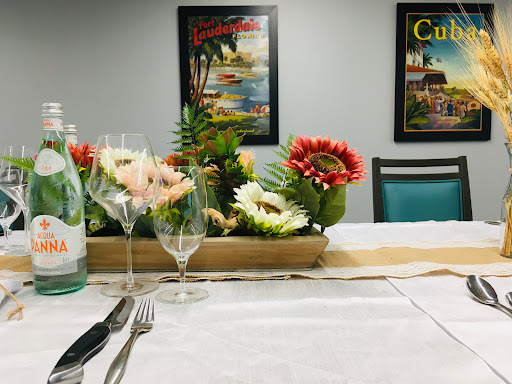 A beautifully arranged table setting featuring a floral centerpiece, elegant glassware, and vibrant wall posters in the background.