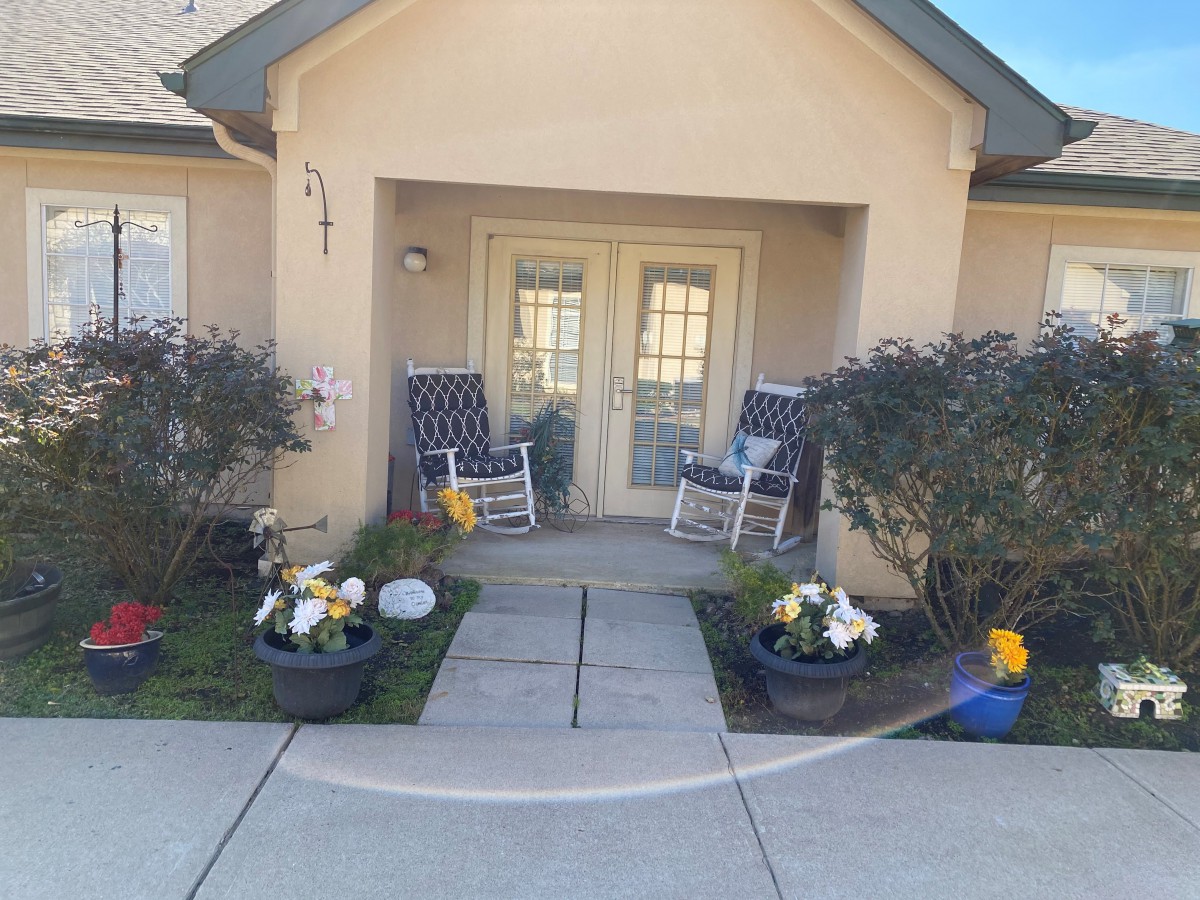 Front porch of a house with rocking chairs and plants.