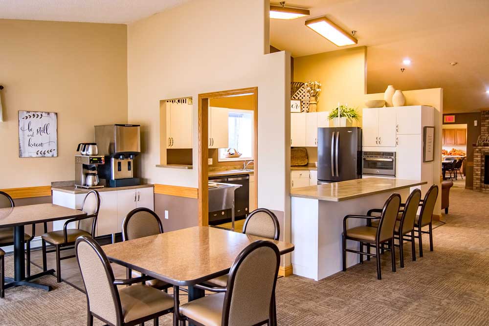 A cozy dining area with a kitchen featuring tables, chairs, and a coffee machine.