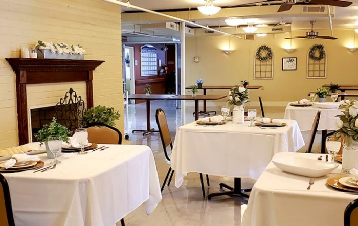 An elegantly set dining area with tables covered in white tablecloths.