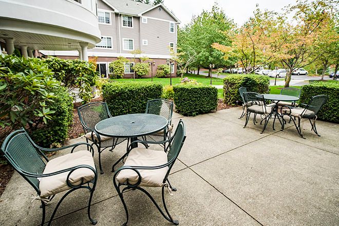A serene outdoor patio with tables and chairs surrounded by lush greenery.