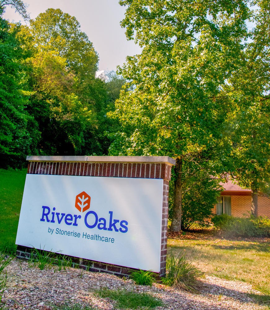 Entrance to River Oaks surrounded by lush greenery.