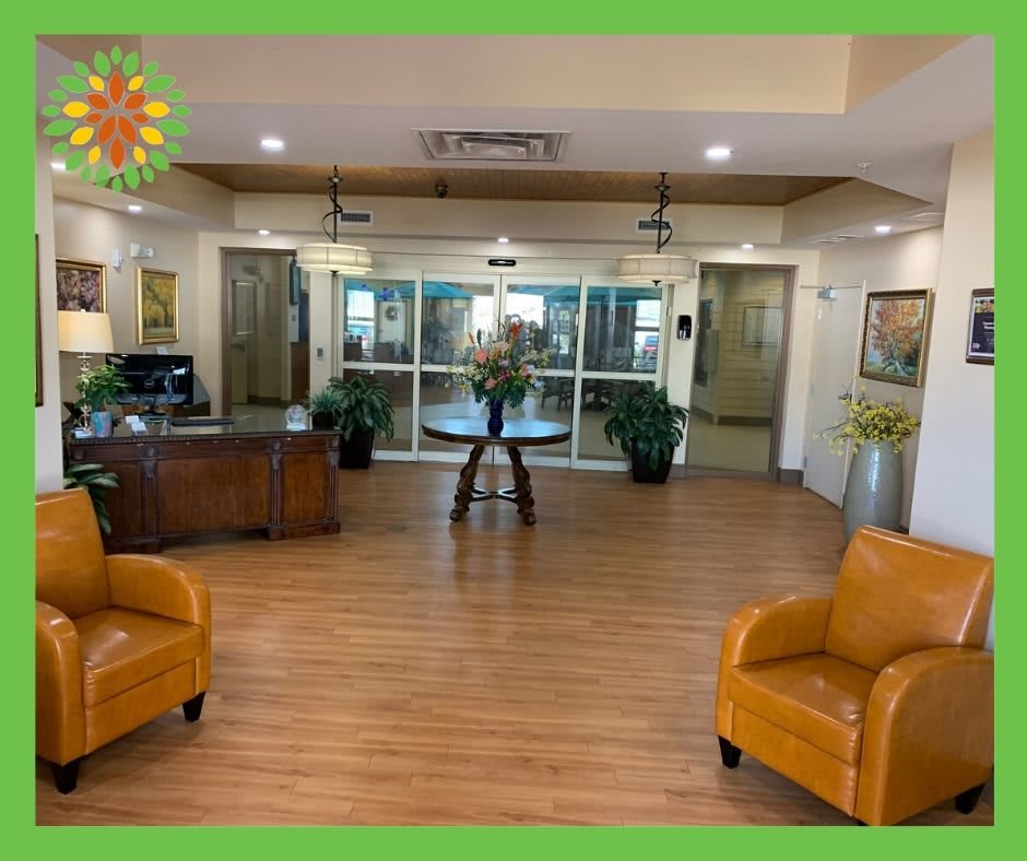 A well-decorated lobby with comfortable seating and a central table, surrounded by decorative plants and artwork.