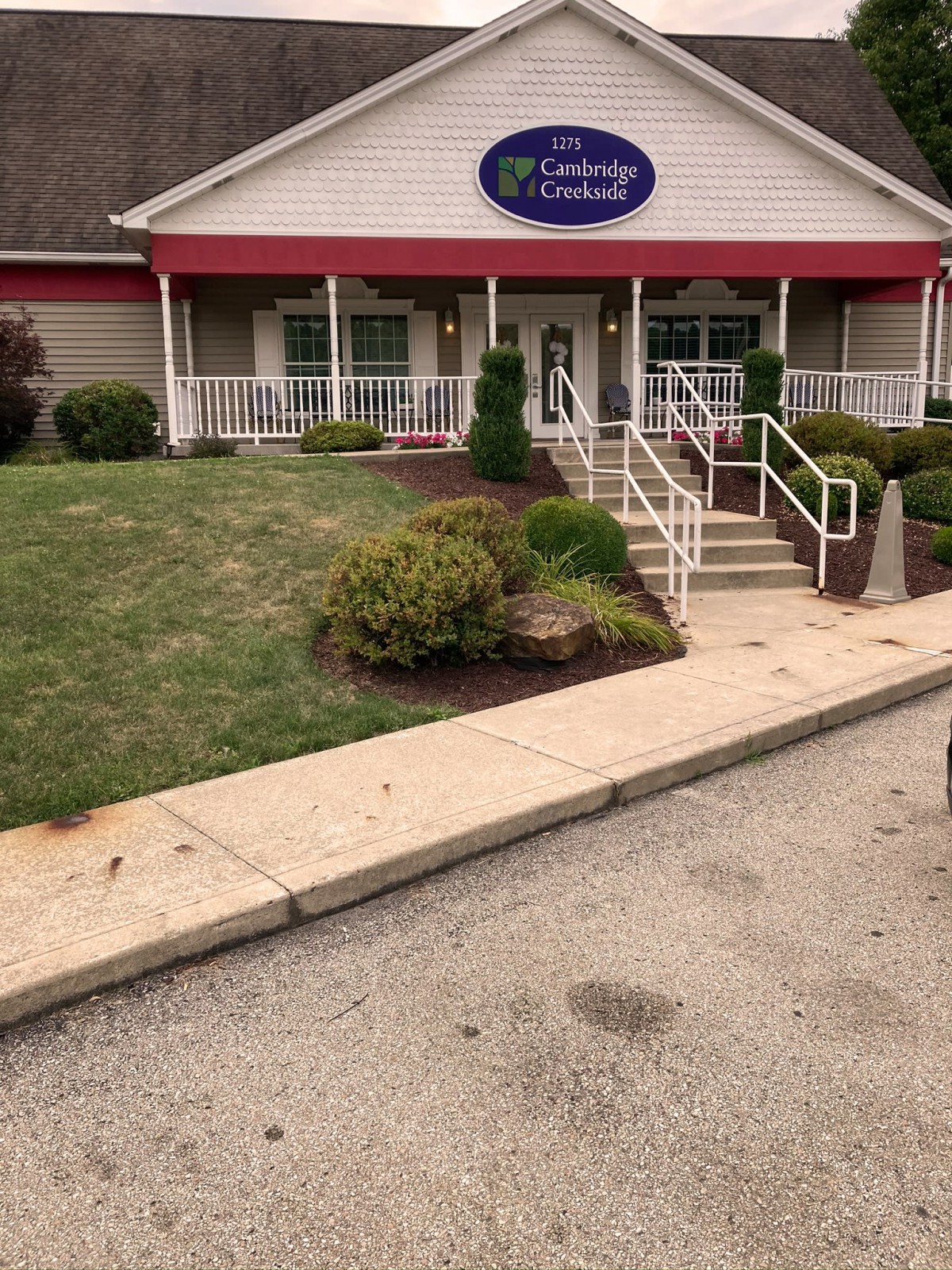 A restaurant entrance with a red awning and landscaped surroundings.