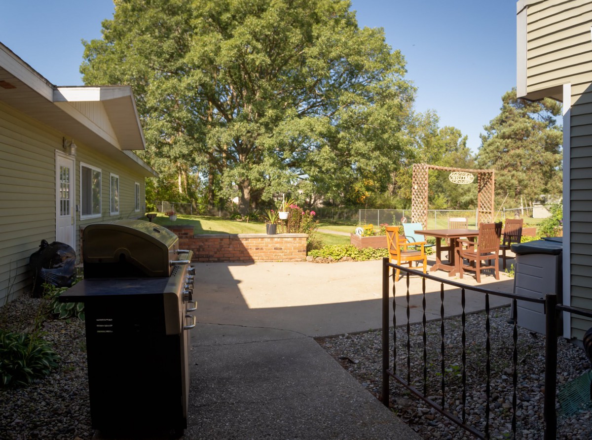 A sunny backyard patio with outdoor furniture and a garden area.