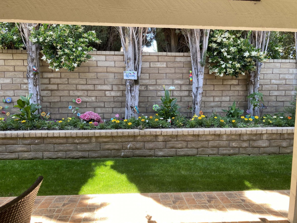 A landscaped garden with a brick wall, colorful flowers, and lush greenery.