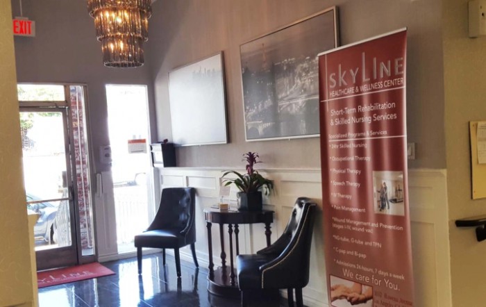 A welcoming waiting area with chairs, a small table with a plant, and a chandelier.