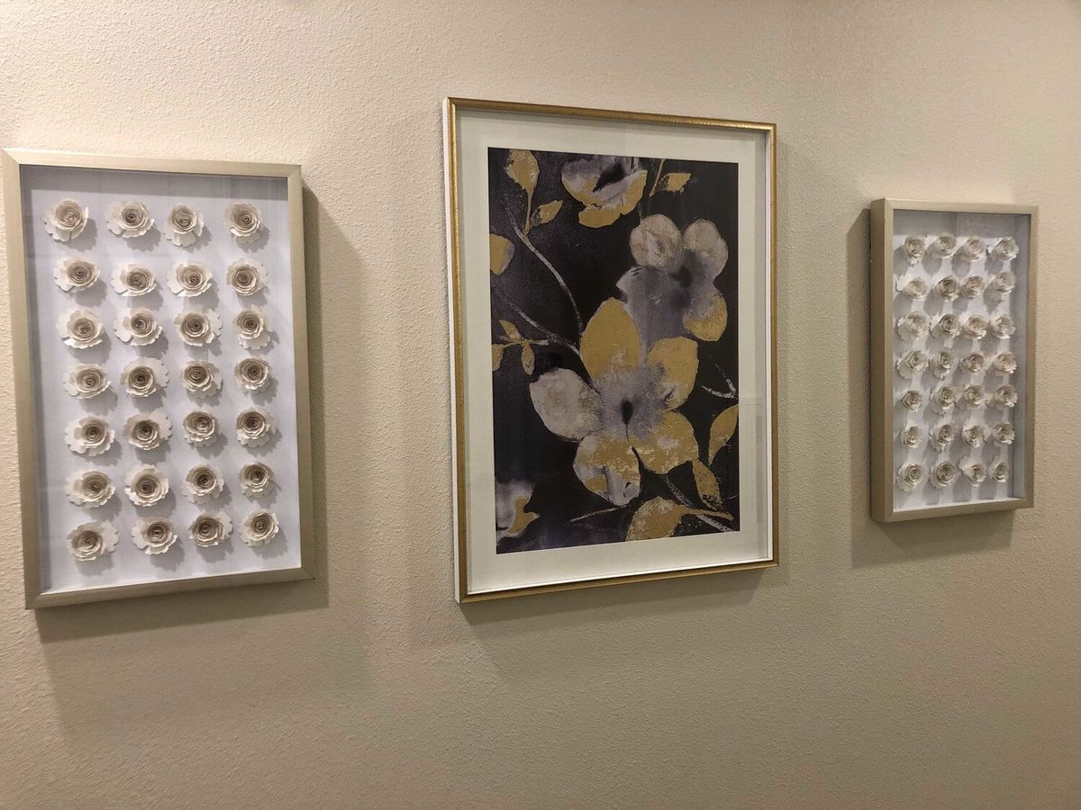 A set of three framed artworks displayed on a wall, featuring floral and abstract designs.