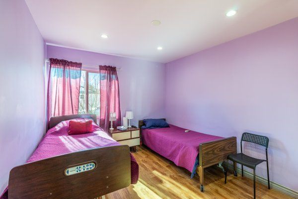 A cozy bedroom with two beds and purple walls.