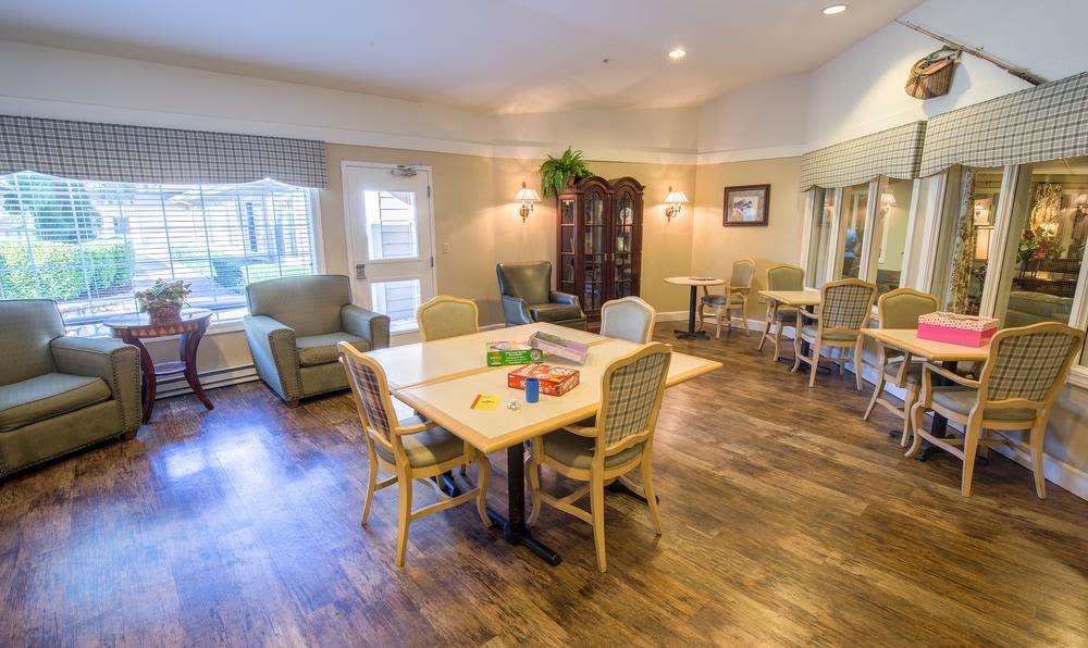 A cozy, well-furnished living room with tables and chairs arranged for social gatherings.