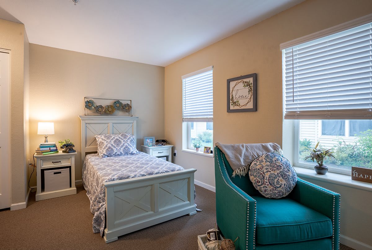 A cozy bedroom with a single bed and an armchair by the window.