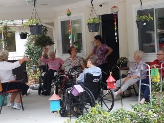 A group of elderly individuals enjoying a conversation outdoors in a nursing home setting.