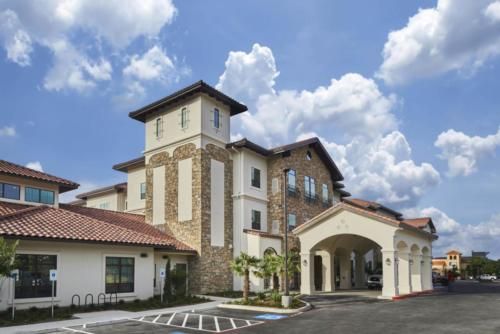 A modern hotel building with a distinctive, elegant architectural design set against a backdrop of a partly cloudy sky.