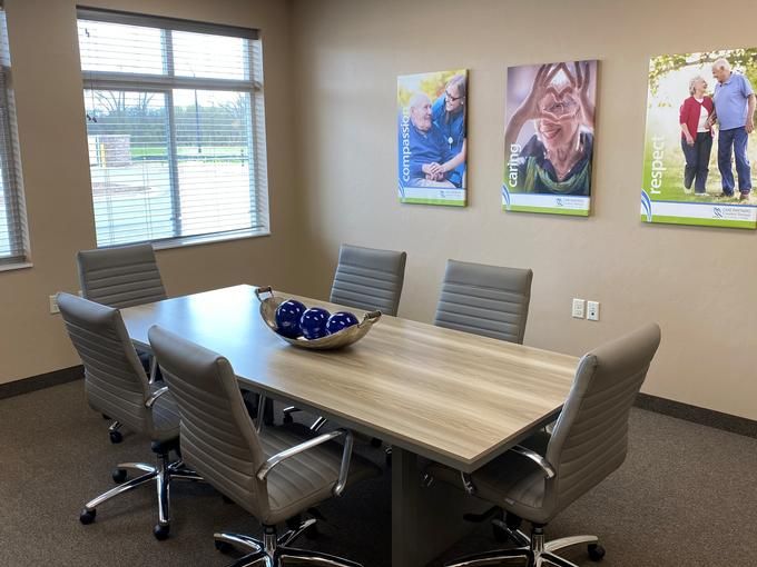 A modern conference room with a large table, comfortable chairs, and artwork on the walls.