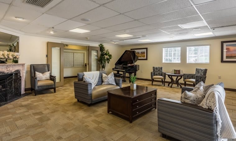 A cozy living room with comfortable seating, a grand piano, and elegant decor.