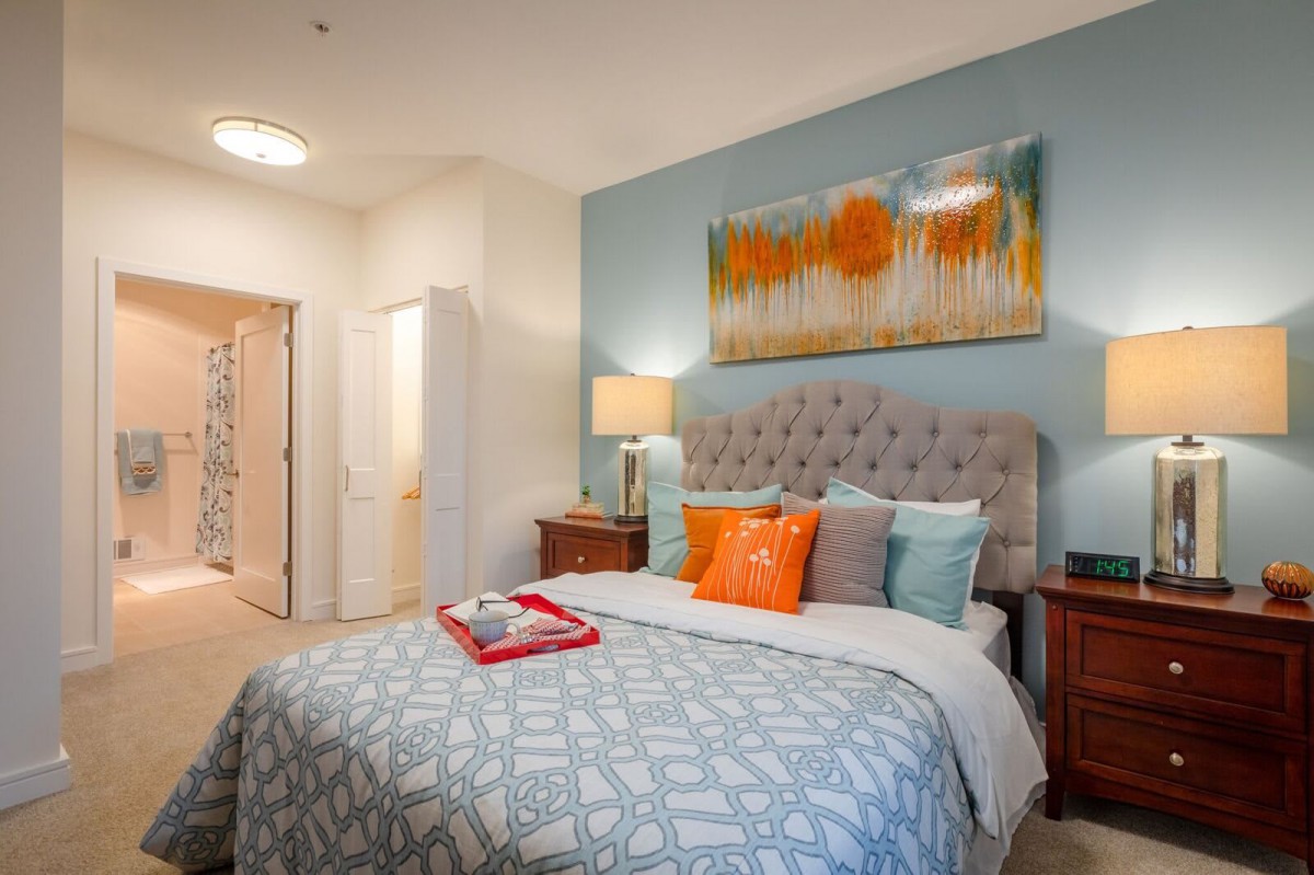 A modern and cozy bedroom featuring a tufted headboard, decorative pillows, and contemporary artwork on the wall.