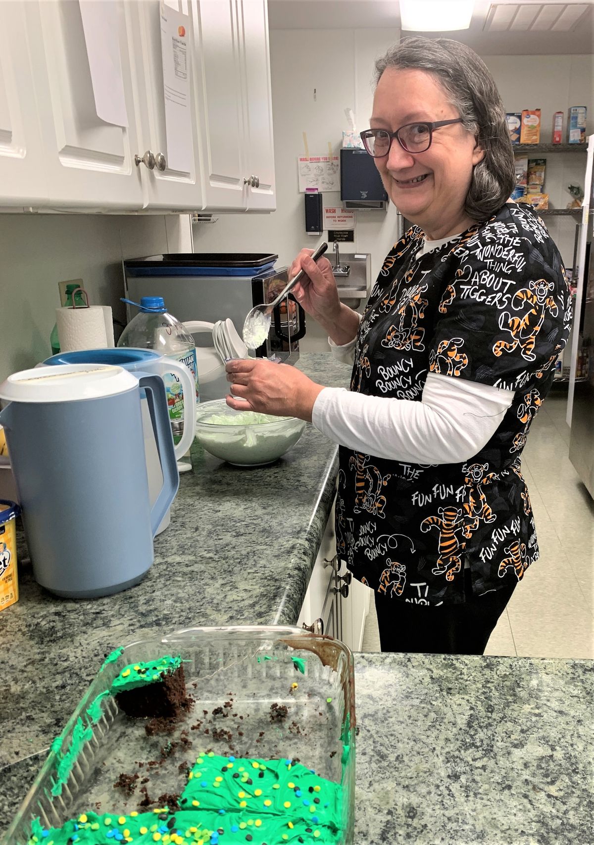A person is smiling while preparing food in a kitchen.
