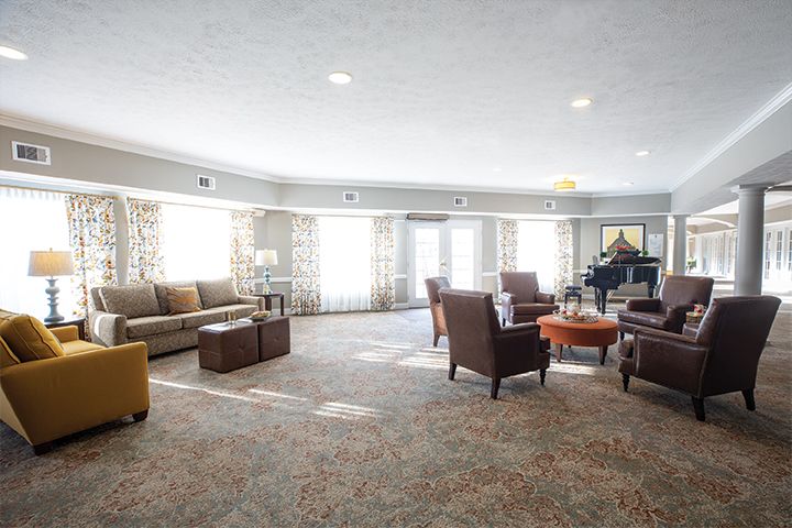 A spacious and well-lit living room with comfortable seating and a grand piano.