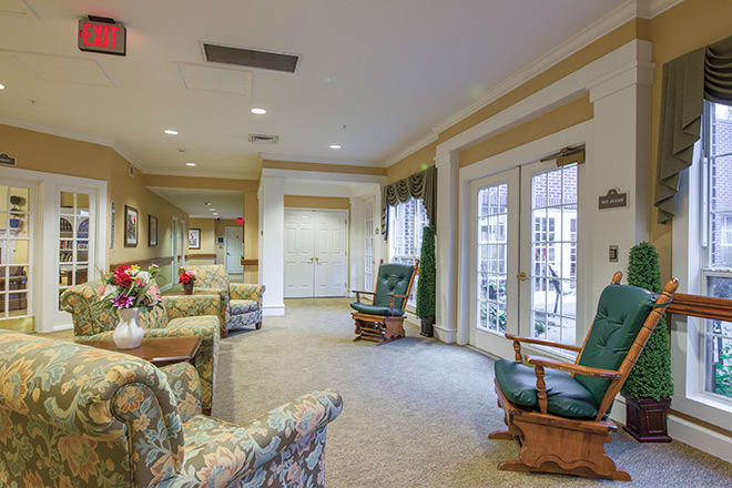 A cozy living room with patterned furniture and large windows.