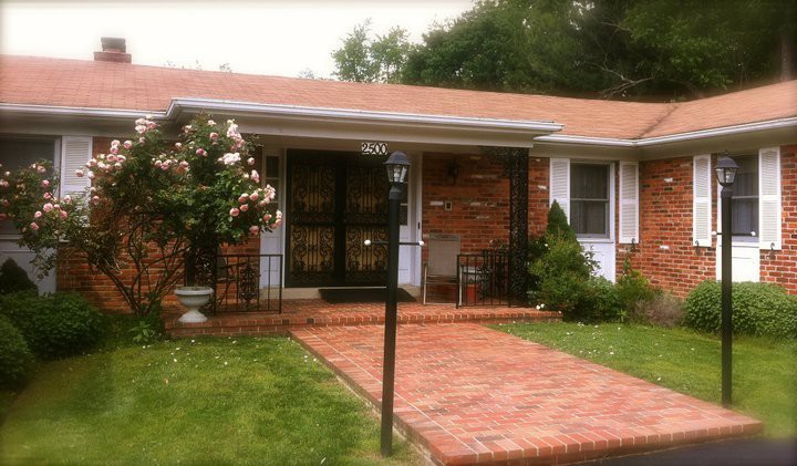 A charming brick house with a small front garden and pathway leading to the entrance.