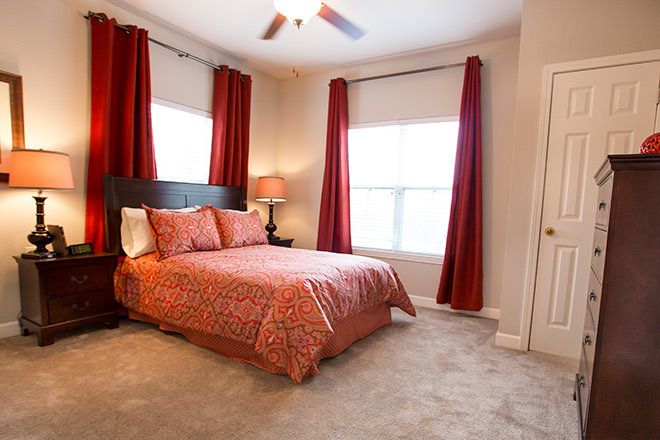 A warmly decorated bedroom with red curtains and a comfortable bed.