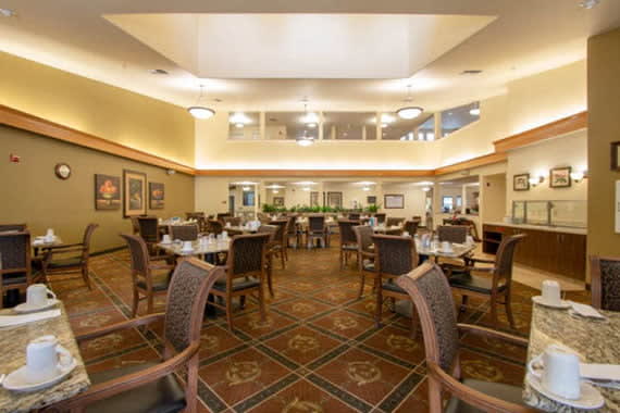 A spacious dining area with neatly arranged tables and chairs, featuring elegant lighting and decor.