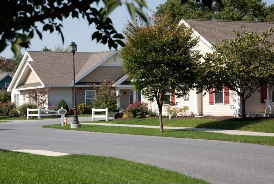 A quiet suburban neighborhood street lined with well-maintained houses and trees.