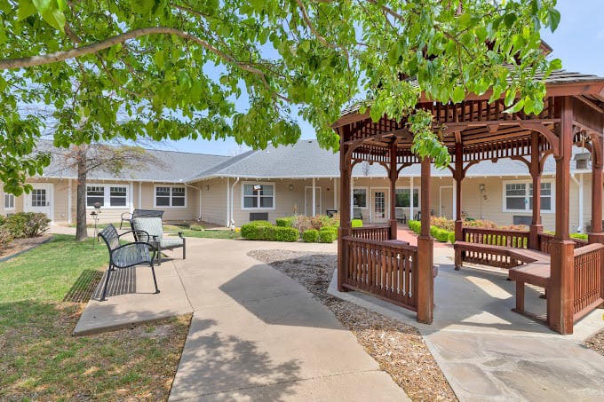 A serene courtyard with a wooden gazebo, benches, and well-maintained landscaping.