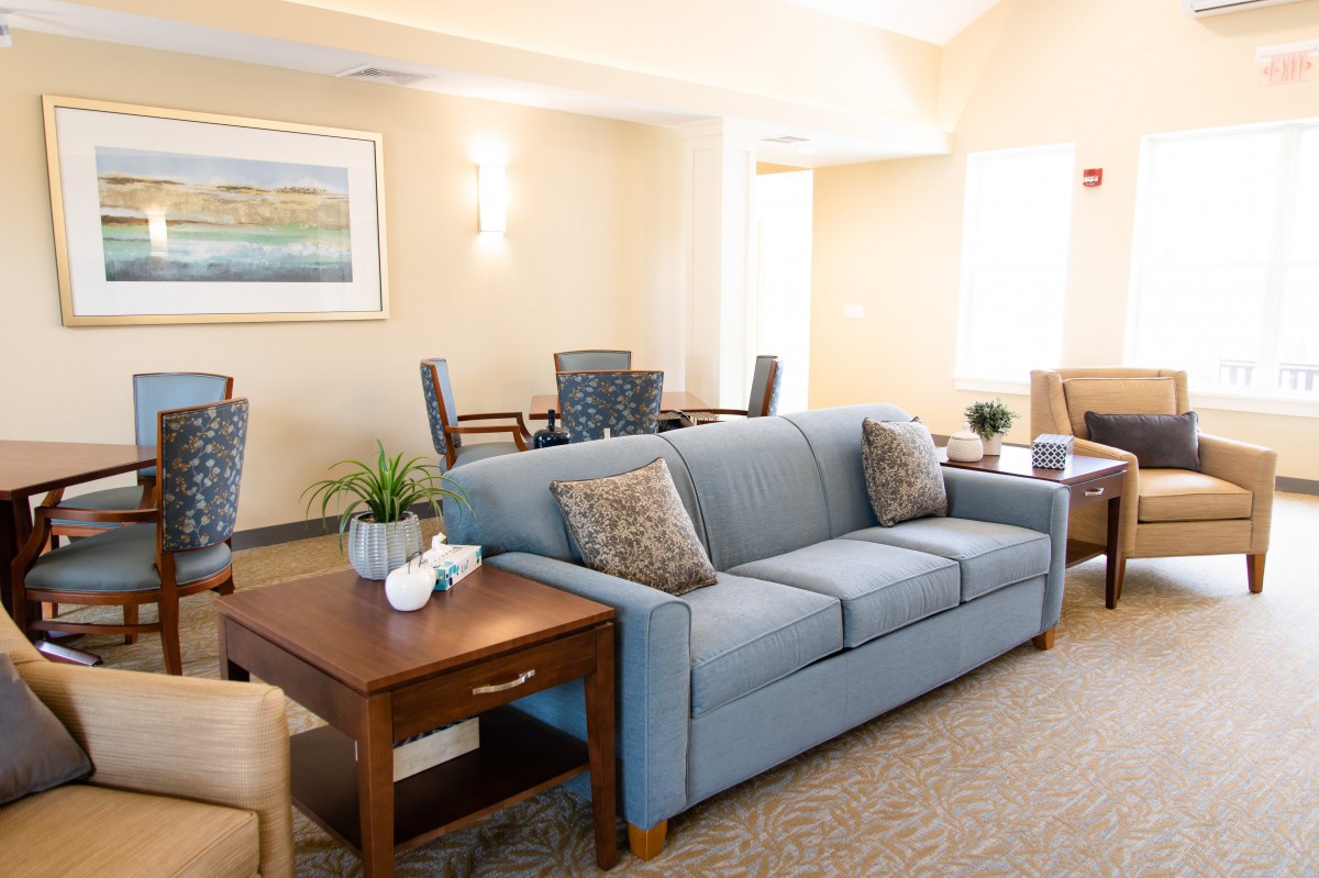 A modern living room featuring a blue sofa and wooden coffee table arranged in a cozy setting with artwork on the wall.