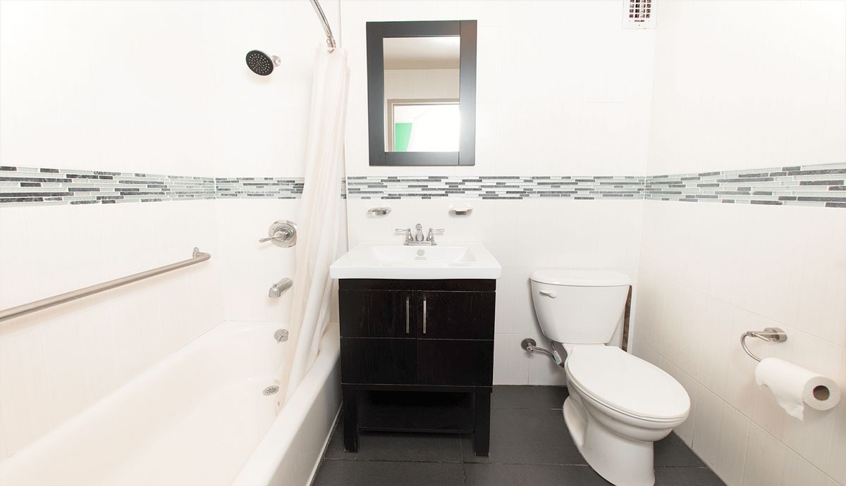 A modern bathroom featuring a sink with a mirror, a toilet, and a bathtub.