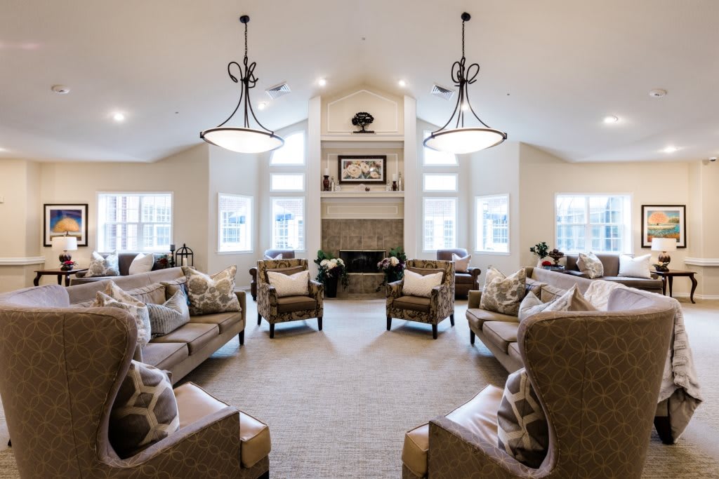 A spacious and elegantly designed living room featuring plush seating, a central fireplace, and stylish chandeliers.