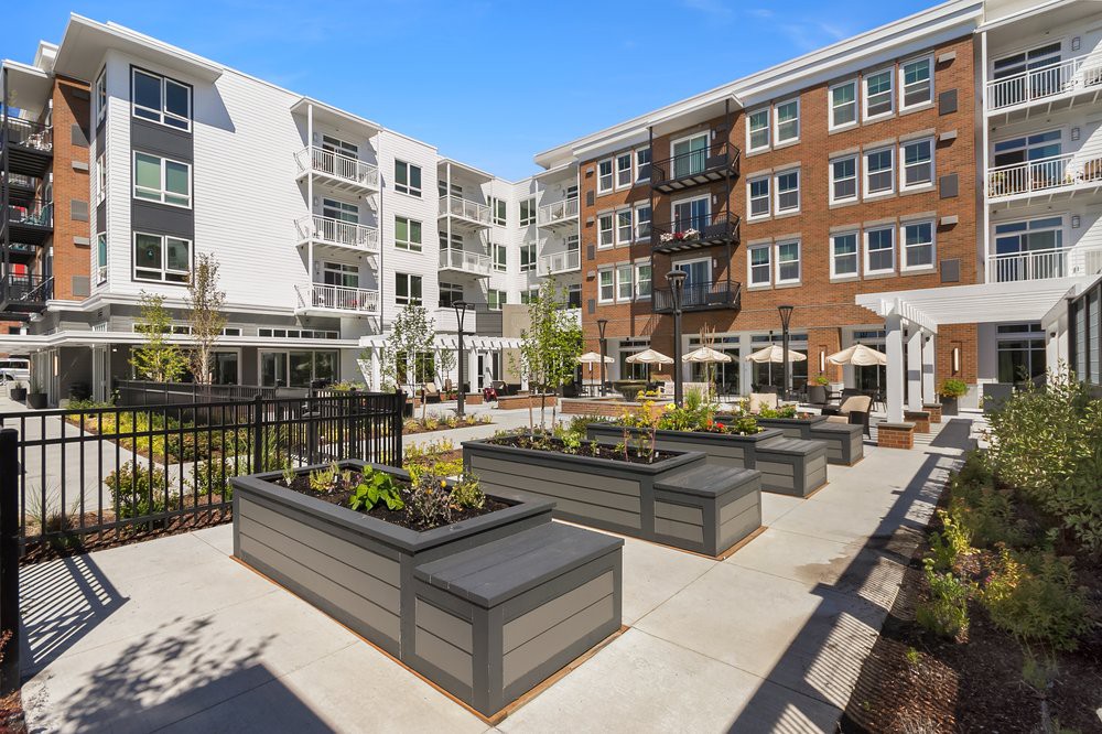 A modern apartment complex featuring a landscaped courtyard with raised planters.