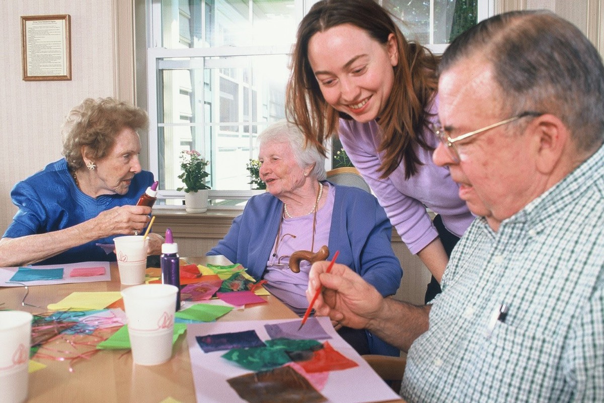 A group of senior citizens enjoy painting together in an art therapy session.