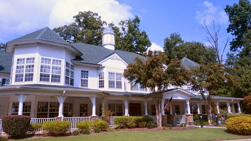 A large residential house with a spacious porch and surrounded by trees.