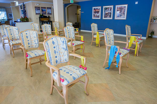 A room with decorated chairs arranged in rows, featuring colorful ribbons on each chair.