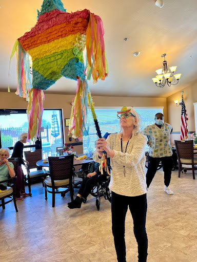 A resident joyfully holds up a colorful piata during a lively community event.
