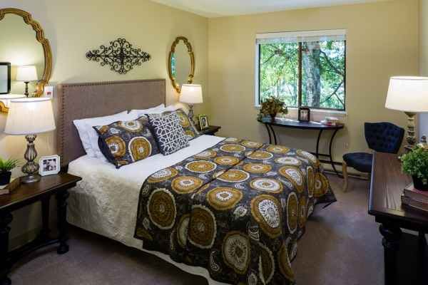 A cozy bedroom with a patterned bedspread, decorative pillows, and a window view.