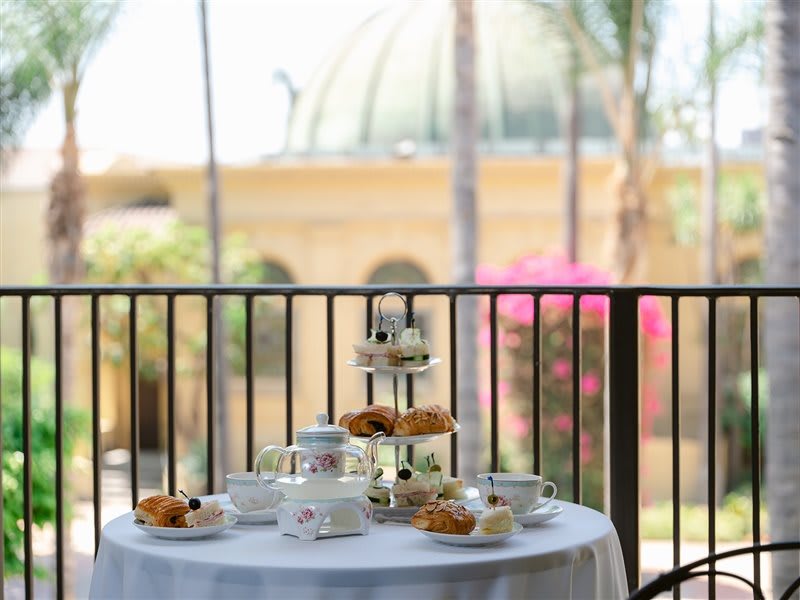 A picturesque outdoor afternoon tea setup with pastries and a tea set on a table.