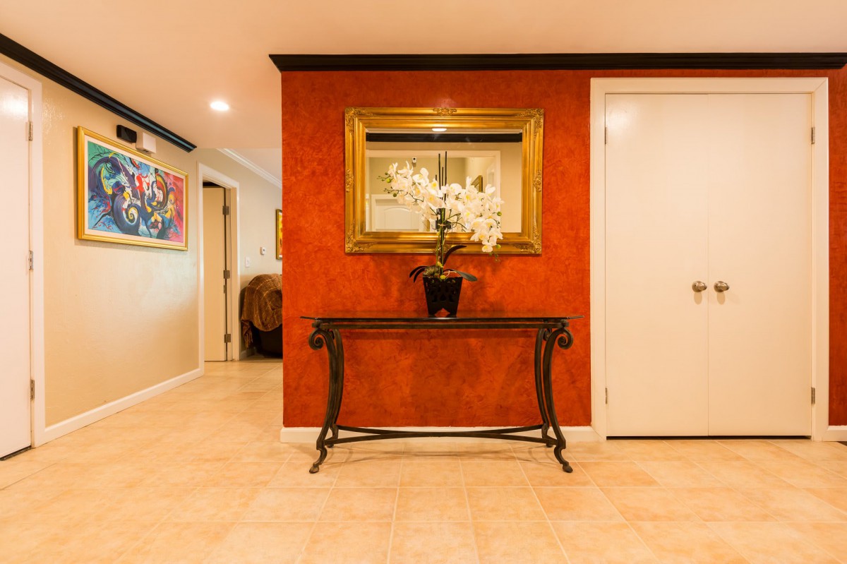 A warmly lit hallway with a decorative table, mirror, and an orchid centerpiece.